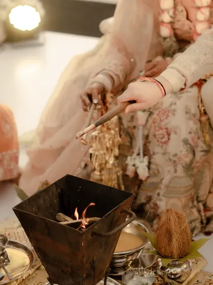 A close-up of the sacred fire (havan) at the heart of the wedding ceremony, with the couple's hands seen performing the ritual. A symbol of their holy union.