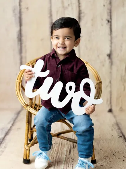 Celebrating a big milestone. This happy toddler is proudly showing off that he is turning two, a perfect memory from our milestone photography sessions.