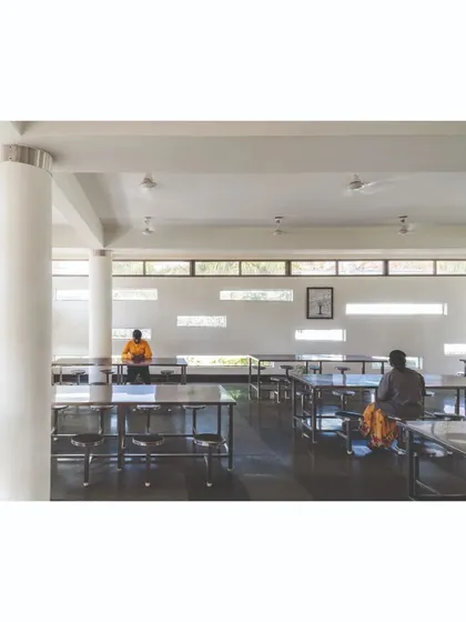 The interior of the factory cafeteria is a simple, functional space designed for durability and ease of maintenance. The slit windows seen on the exterior facade allow controlled natural light to enter, creating a calm and pleasant dining environment.