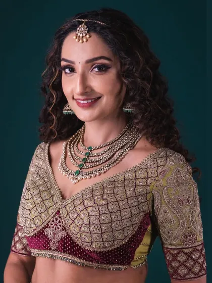 A portrait of the model, highlighting the beautiful craftsmanship of the Banarasi lehenga blouse and the elegant layered necklace.
