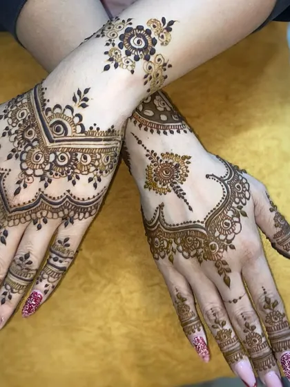 This showcases a modern Arabic mehandi style. The design uses negative space effectively, with flowing vines and bold floral elements on the hands and wrist for a chic and contemporary feel.