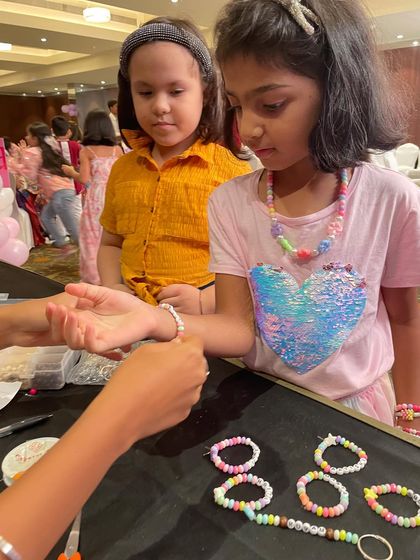 Helping a little mermaid craft her very own beaded bracelet. It's a great activity for developing fine motor skills while having fun with friends.