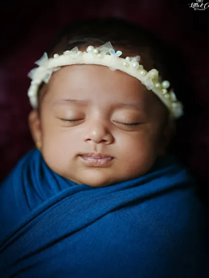 A serene close-up of a newborn's face, highlighting their perfect, delicate features. We use careful lighting to capture every tiny detail.