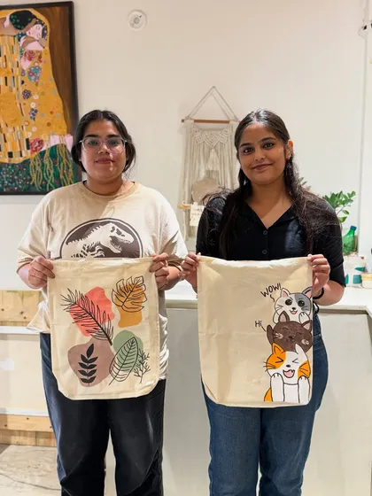 Tote bag painting is a fun and practical activity. These two friends created their own custom designs, one with abstract botanicals and the other with cute cartoon cats.