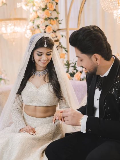 A key moment from the ring ceremony. The groom gently places the ring on the bride's finger, their smiles reflecting the significance of the moment.