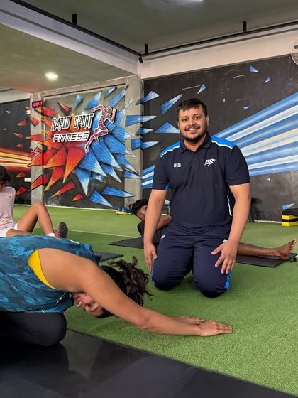 A coach smiles as he guides a client through a mobility exercise. Our team is dedicated to providing expert guidance in a supportive and positive environment.