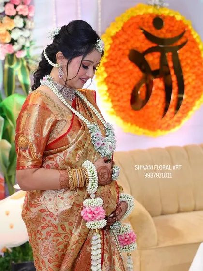 A touching moment from a baby shower, with the mom-to-be wearing a white and pink floral set. The custom 'Maa' floral decoration in the background adds a personal touch to the event.