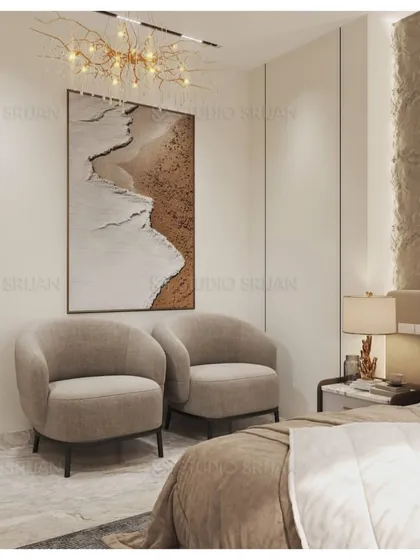 A cozy seating corner in the bedroom, with two comfortable armchairs and a piece of art depicting a serene beach scene, enhancing the room's tranquil vibe.