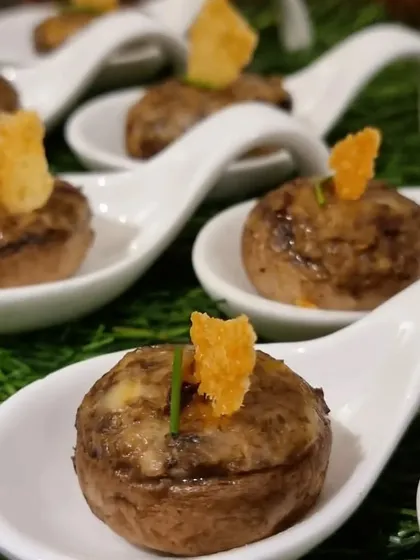 Funghi Ripieni, or stuffed mushrooms, served on tasting spoons. A classic Italian appetizer that's always a crowd-pleaser.