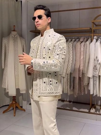 A modern and chic Indo-western outfit. This white jacket features unique cutwork detailing, worn over a simple kurta. It's a high-fashion look for the style-conscious groom or guest.