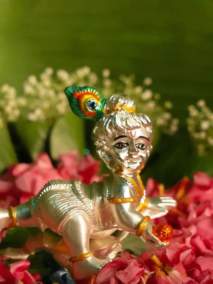 The playful spirit of Ladoo Gopal is captured in this crawling Krishna idol. The silver-plated finish and peacock feather detail make it a charming and auspicious piece for celebrating Janmashtami.