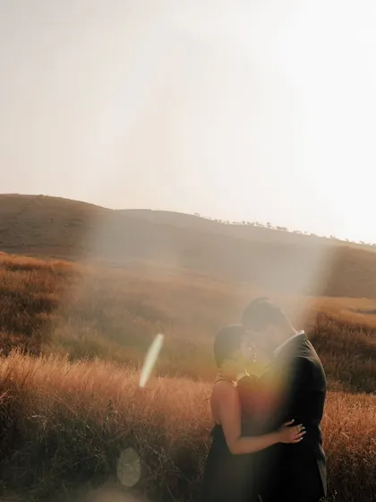 A romantic embrace against a bright, hazy sky, with lens flare adding a magical, cinematic quality to the image.