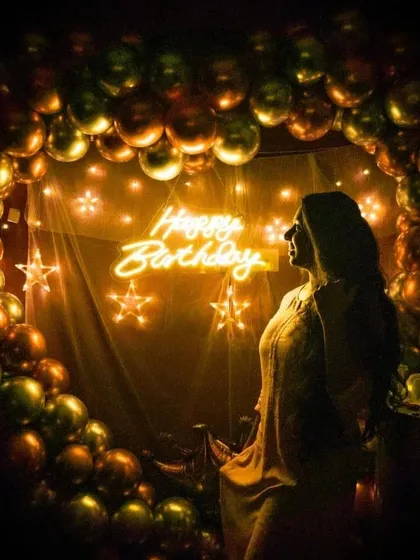 I love how creative you can get with photos in the theatre. The glow from the 'Happy Birthday' neon sign and the balloon arch creates a perfect backdrop. This is a great example of a birthday photoshoot before the movie starts.