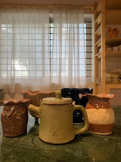 A delightful collection of hand-built pieces from one of our youngest students. This set includes a star-stamped teapot, a two-toned vase, and other imaginative creations, all fresh from the kiln.