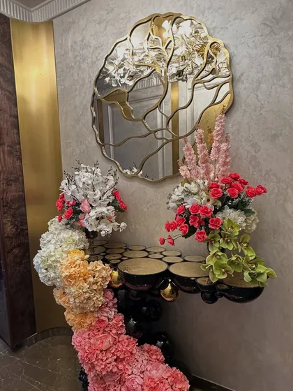This home wedding decor features a stunning floral installation that flows from a console table and frames a doorway, using a beautiful ombre effect with pink, orange, and white flowers.
