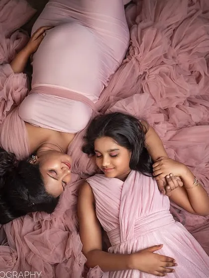 A beautiful overhead shot capturing the quiet connection between a mother and her daughter. They lie peacefully on the sea of pink tulle, creating a soft and dreamy image.