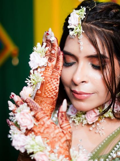 A close-up showing the beautiful dark stain on the hands, complemented by delicate floral jewelry. This is the perfect look for a mehndi or haldi ceremony.