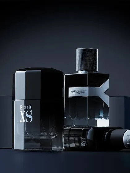 Lock, stock, and three smoking barrels. This group shot features fragrances from YSL and Paco Rabanne. The monochrome blue lighting and geometric blocks create a cool, modern, and architectural composition that unifies the different bottle shapes.
