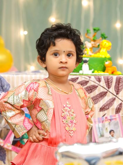 A cute portrait of the birthday girl striking a pose in front of her party setup.