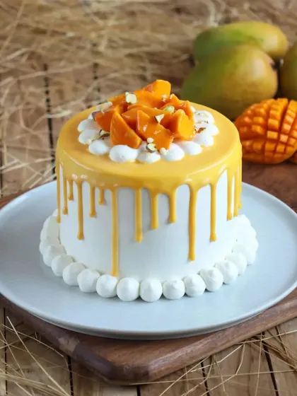 A close-up of our mango drip cake, showcasing the glossy drip and the fresh mango and nut topping.