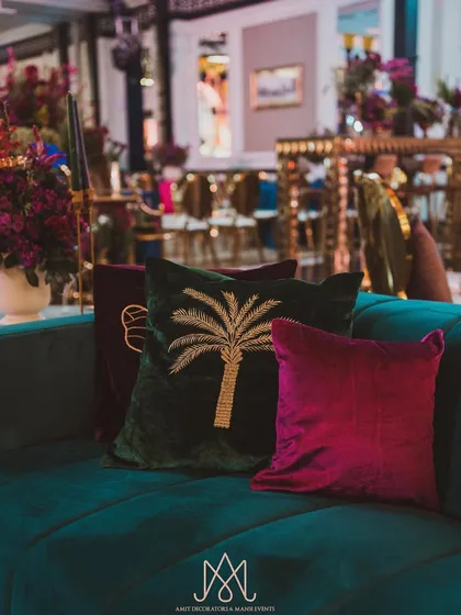 A collection of custom velvet cushions in jewel tones with embroidered motifs like palm trees, adding personality and comfort to the lounge sofas.