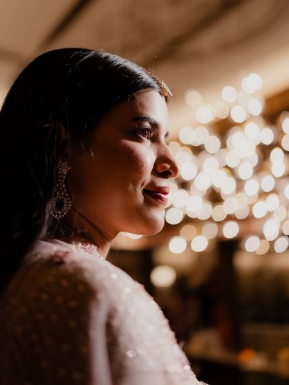 A close-up portrait of the bride during her Sangeet. The beautiful bokeh from the background lights adds a magical quality, highlighting her serene smile and happiness.