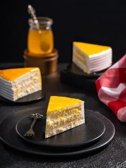 Slices of a bright yellow mango pastry arranged on dark plates, creating a strong contrast that makes the dessert pop.