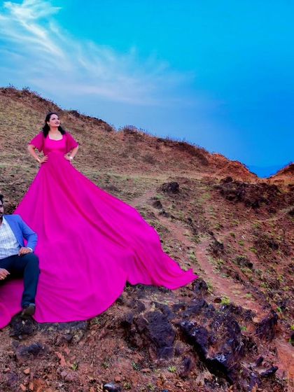 This epic pre-wedding shot on a mountainside showcases one of my most dramatic flying gowns. The vibrant pink fabric creates a stunning visual against the blue sky.