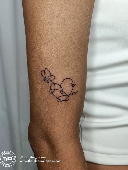 A single-line tattoo that elegantly combines a heart, a butterfly, and a flower. This continuous line design symbolizes love, transformation, and growth in one seamless, minimalist piece.