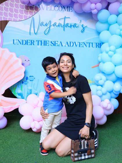 A guest gives the camera a warm hug in front of the mermaid backdrop. Our parties are full of love and happy moments.