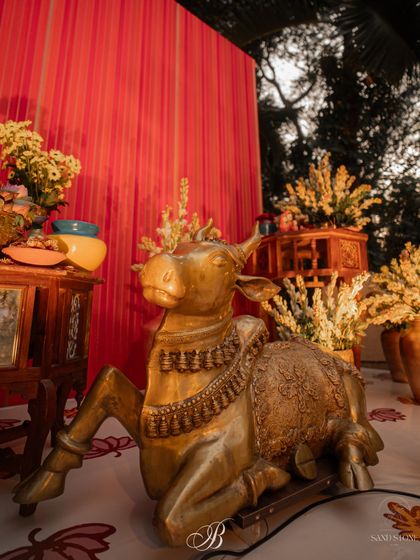A magnificent brass Nandi statue sits proudly before the red dupatta backdrop. I love using large, statement brass pieces to add a sense of grandeur and timeless Indian tradition to the decor.