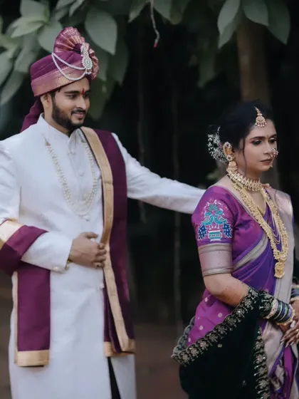 A candid moment between the bride and groom, showcasing the bride's intricate hairstyle with floral accessories and the groom's coordinated turban.