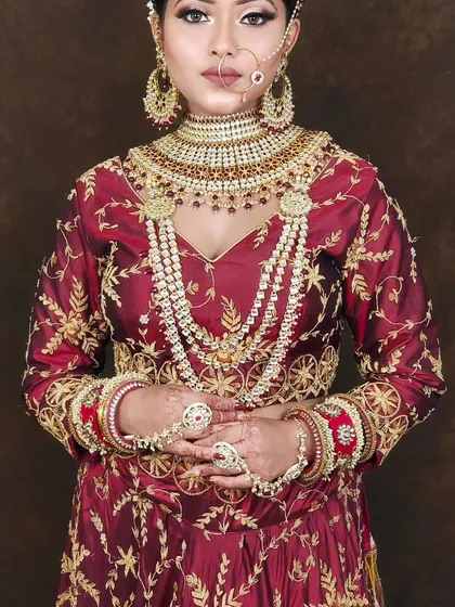 This outfit shows a rich maroon Anarkali-style lehenga with intricate gold embroidery, paired with a heavy, multi-layered Polki necklace set.