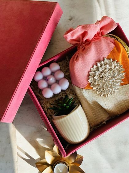 This 'Luxe Pink Box' is a modern take on a traditional hamper. It includes a Gota trail mix potli, a bubble candle, and a small plant, blending aesthetic, sustainable, and useful elements perfectly.