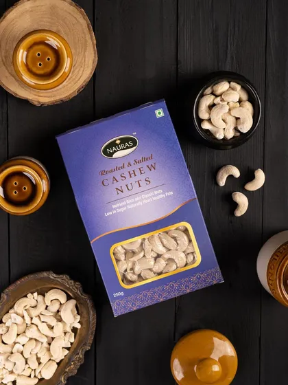 A dark and moody flat lay of Nauras Roasted & Salted Cashew Nuts. The dark background makes the blue packaging stand out, creating a premium look.
