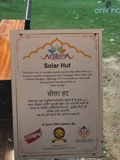The official signage on our Solar Hut in Ayodhya. It details the public amenities offered in both English and Hindi, including free 24/7 access to mobile charging, CCTV surveillance, and a safe seating area, all powered by solar energy.