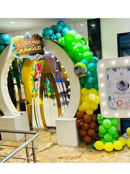 A fantastic 'Welcome to the Jungle' entrance arch with a mirrored background, surrounded by green and brown balloons to create a forest feel.
