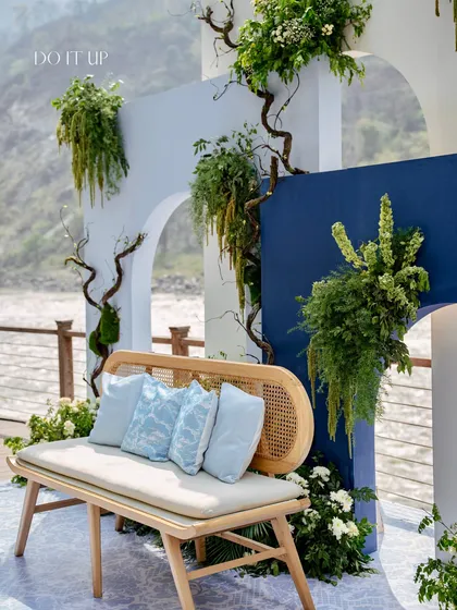 A side view of the modern Mehndi backdrop by the Ganges. The design plays with layers and arches, with wild greenery adding a touch of nature against the serene river view.