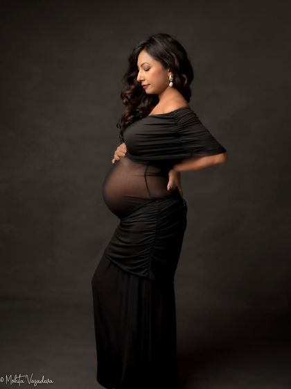A classic black silhouette. This elegant, form-fitting gown with sheer fabric is perfect for highlighting the beautiful shape of your baby bump in a sophisticated way.