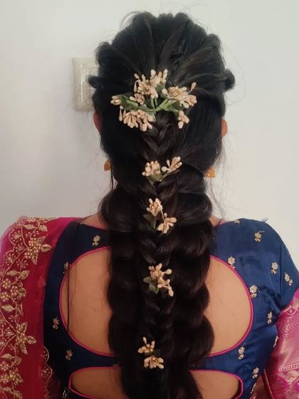 This intricate braid combines different weaving techniques and is accessorized with small, delicate flowers for a modern yet traditional feel. It's a beautiful choice for a wedding guest.