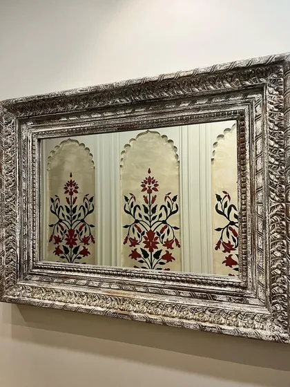 A reflection in a mirror showing my hand-painted Mughal-style floral motifs. The ornate frame and the reflection create a beautiful, layered composition.