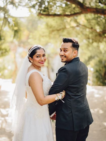 A joyful, over-the-shoulder glance from the bride. This candid shot captures the happiness and excitement of the wedding day in a beautiful garden setting.