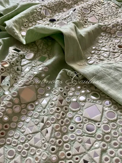 A detail shot of the palazzo's fabric, showing the dense and reflective mirrorwork.