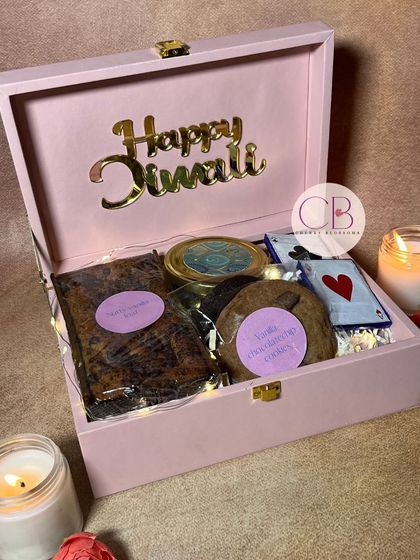 Light up your Diwali with our budget-friendly confectionery hampers. This beautiful pink box with a "Happy Diwali" acrylic cutout is filled with our homemade dry cake, cookies, and cracker chocolates.