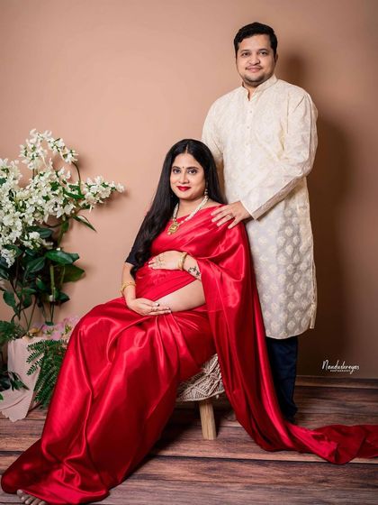 A formal seated portrait of the couple. This is a timeless shot that captures the elegance and grace of the expecting parents in their traditional wear.