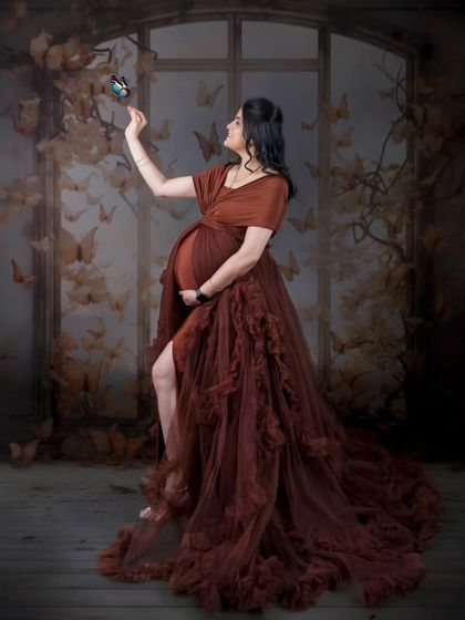 A whimsical and artistic solo portrait. The mom-to-be is surrounded by a flight of butterflies, creating a magical atmosphere of transformation and new life.