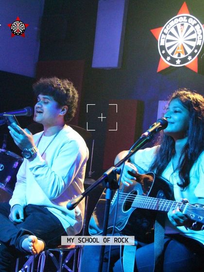 A beautiful shot of a duo performing, with one on vocals and the other on guitar. Collaborations are always welcome and create magical moments on our stage.