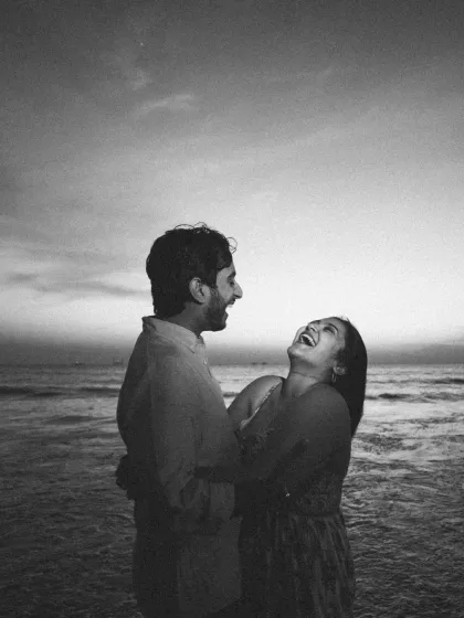 There is a special kind of magic in black and white. This image strips away everything but the pure, uninhibited laughter between two people. It’s a raw, real moment of connection by the sea.