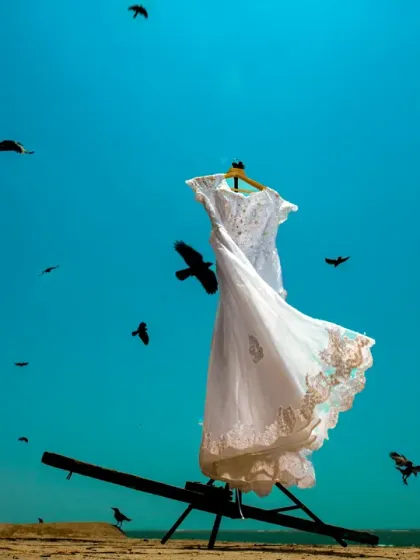 A dramatic shot of the wedding dress against a vivid blue sky, with birds flying past. This turns a simple dress shot into something epic and memorable.