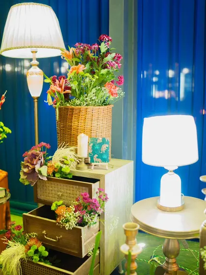 A creative floral display using a chest of drawers, with flowers spilling out of the open drawers. This unique arrangement, paired with soft lamp lighting, adds a touch of whimsy and charm.